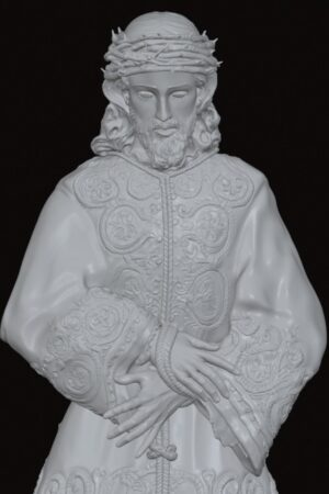 White sculpture of Jesus wearing a crown of thorns and elaborately embroidered robes, hands crossed at the waist against a dark background