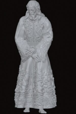 White ornate statue of a bearded man in a long embroidered robe standing with hands clasped, set against a dark background—detailed floral patterns along the sleeves and hem.